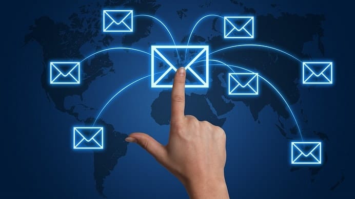 Hand touching central email icon surrounded by glowing envelope symbols on world map background.